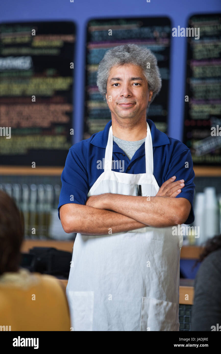 Confident mature Arab cafe waiter with apron Stock Photo