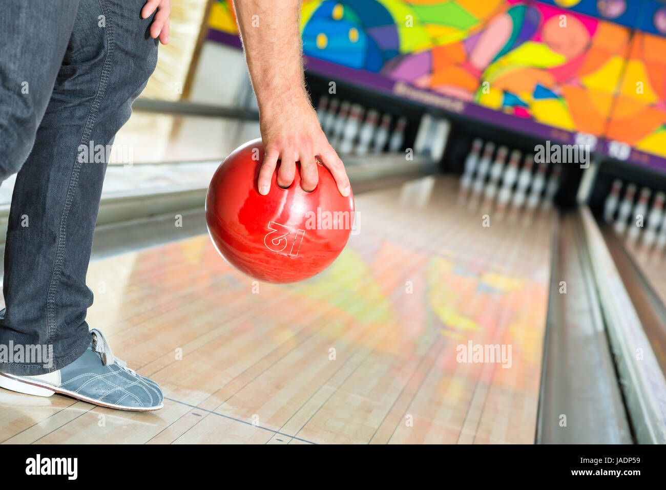 Young man in bowling alley having fun, the sporty man holding a bowling ball in front of the ten pin alley Stock Photo