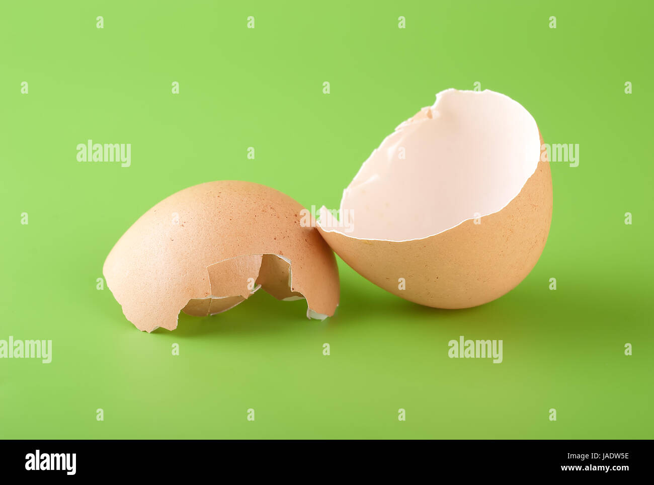 Two pieces of brown egg shell on a green background Stock Photo - Alamy
