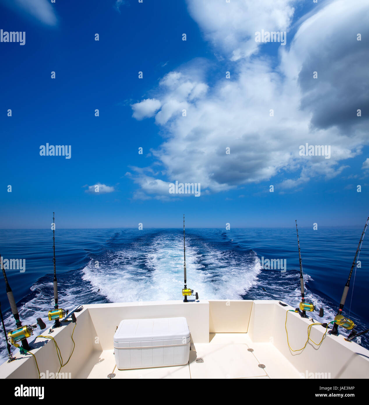 Fishing boat stern deck with trolling fishing rods and reels in blue ocean sea Stock Photo