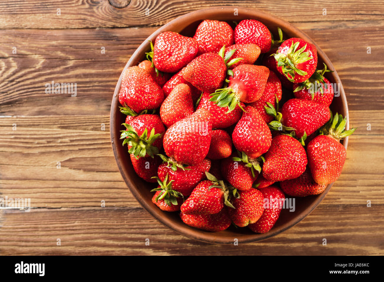 Ripe strawberry in a bowl on wooden background Stock Photo - Alamy