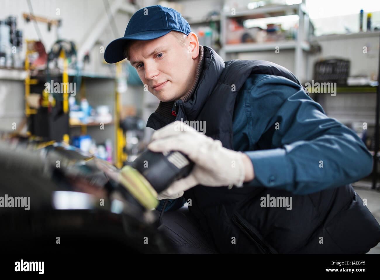 Sports car in a service workshop - machanic polishing car body Stock Photo