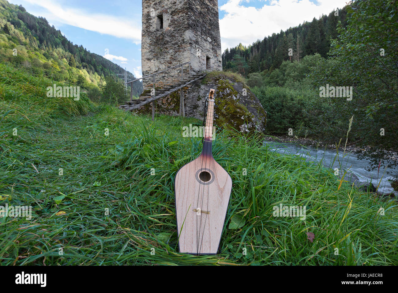 Georgian national musical instrument of Panduri with a medieval tower in the background, in the Svaneti region of the Caucasus Mountains, in Georgia. Stock Photo