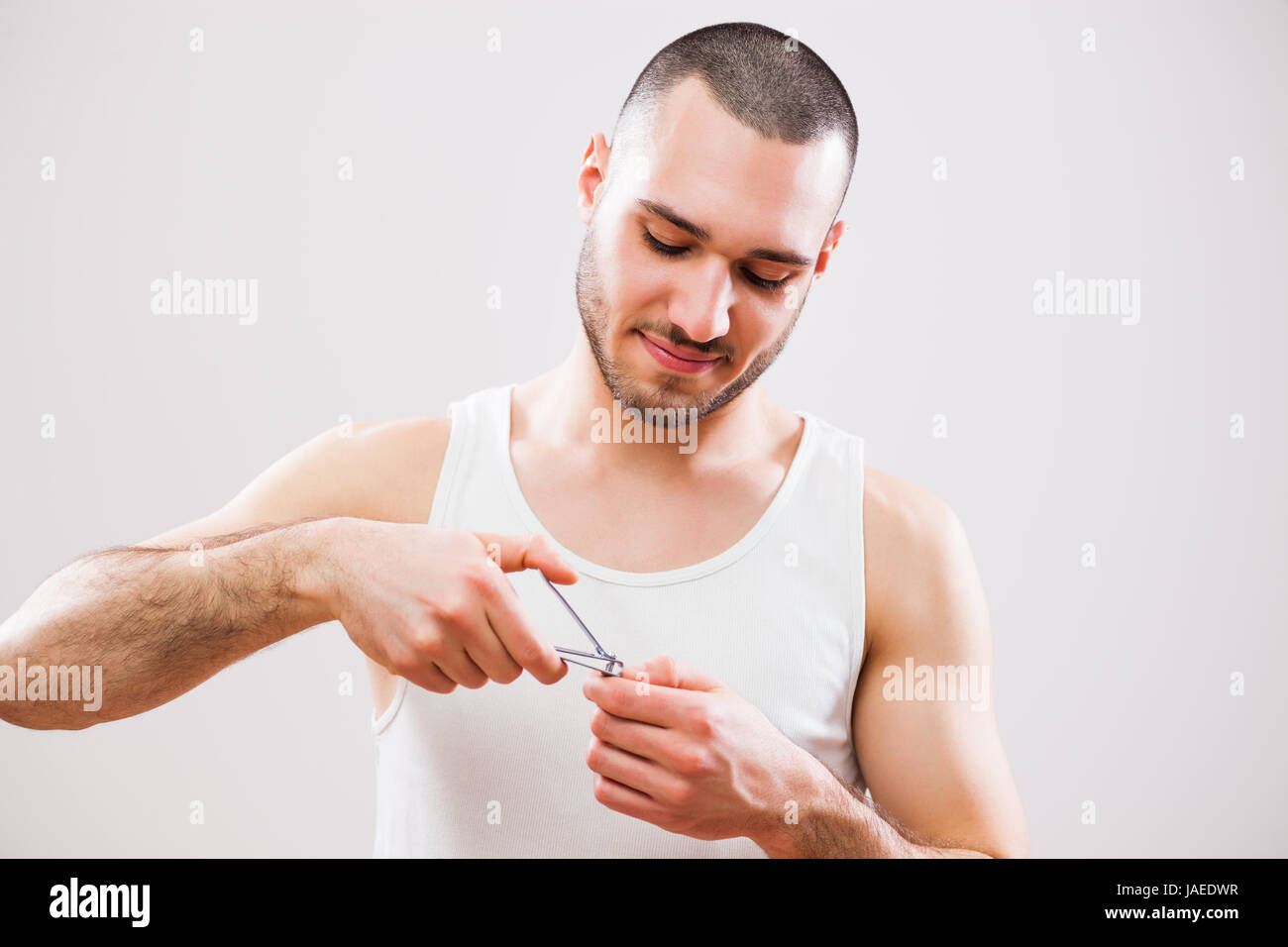 Young man is cutting his nails. Studio shot. Stock Photo