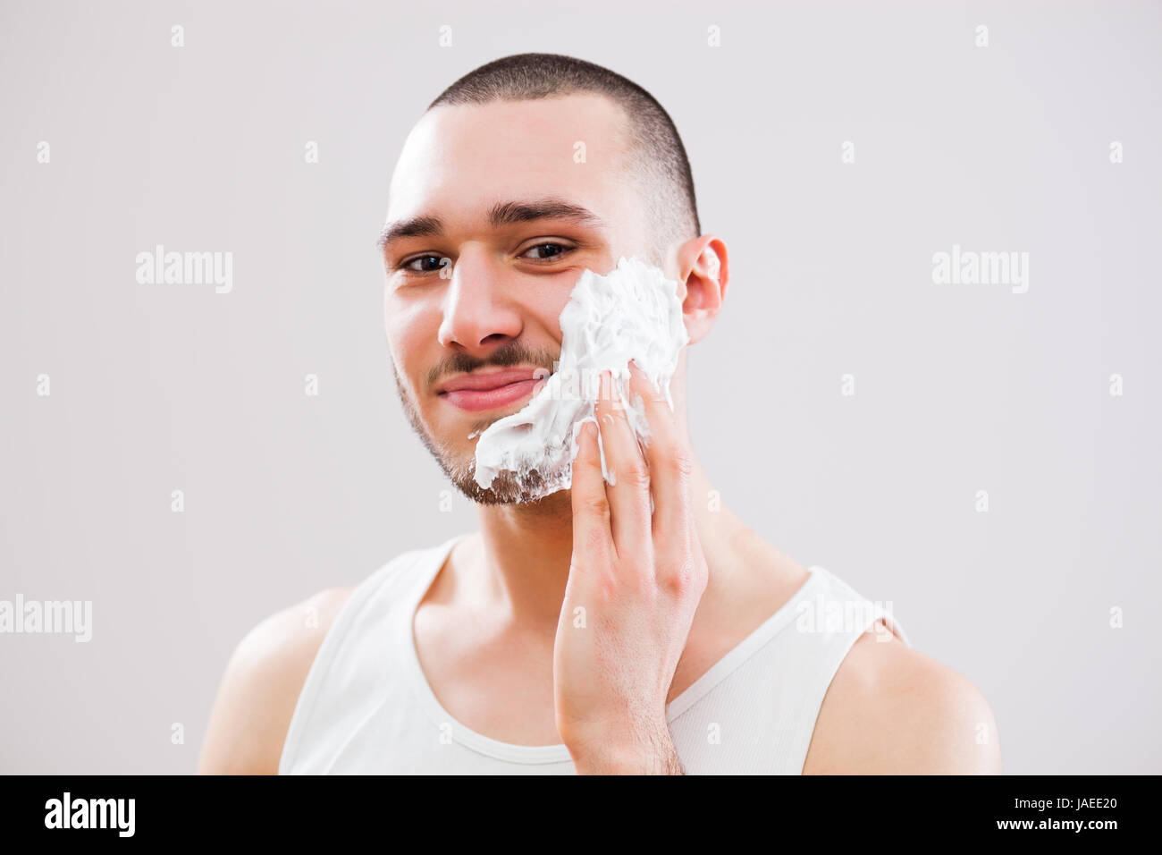 Young man is applying shaving cream to his face Stock Photo Alamy