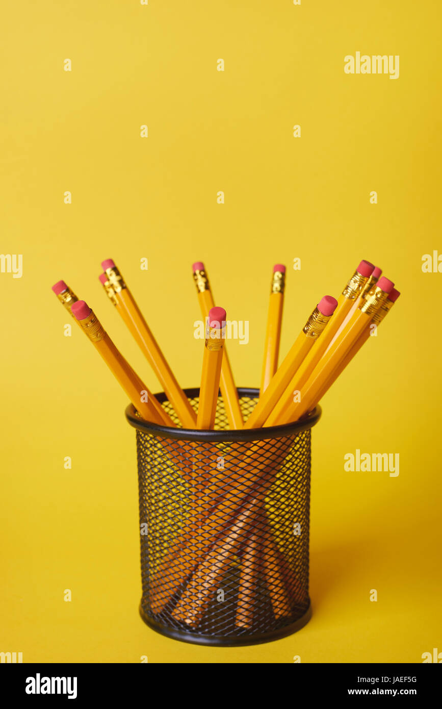 Pencils In Desk Organizer Against Yellow Background Stock Photo