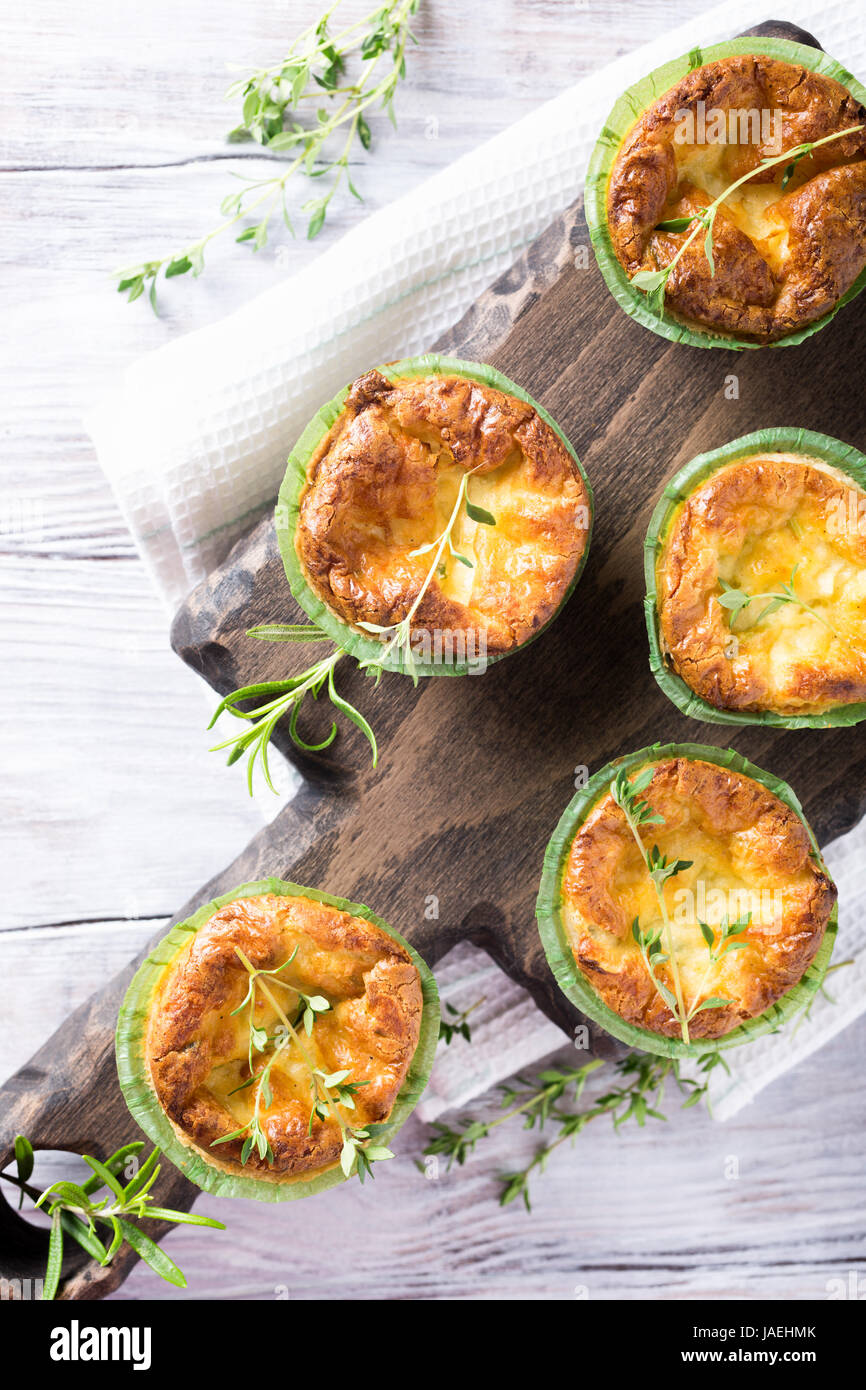 Savory cheddar cheese and leek mini quiches with thyme on dark wooden