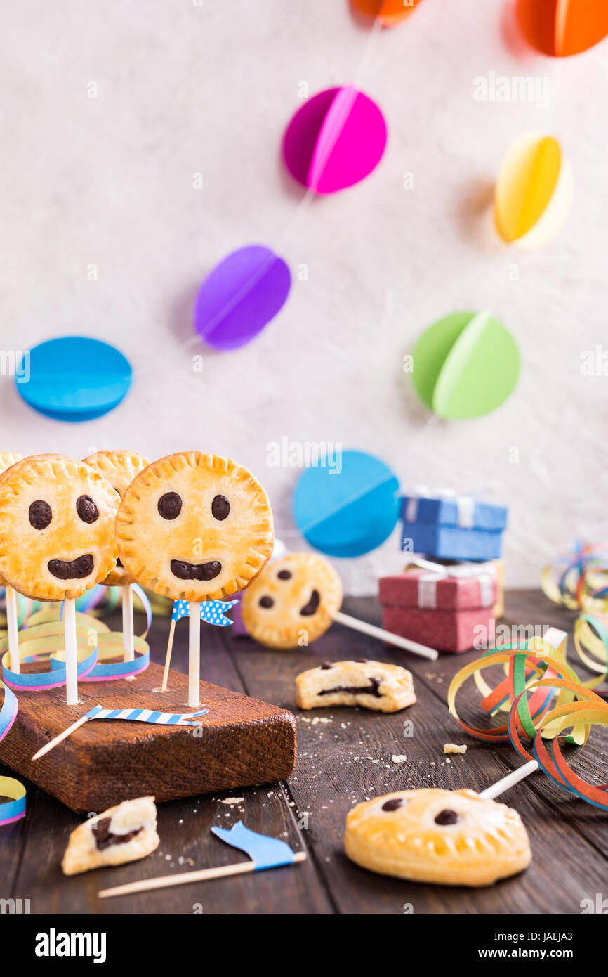 Homemade shortbread smiley cookies with dark chocolate on stick called pie pops. Childrens party background. Stock Photo