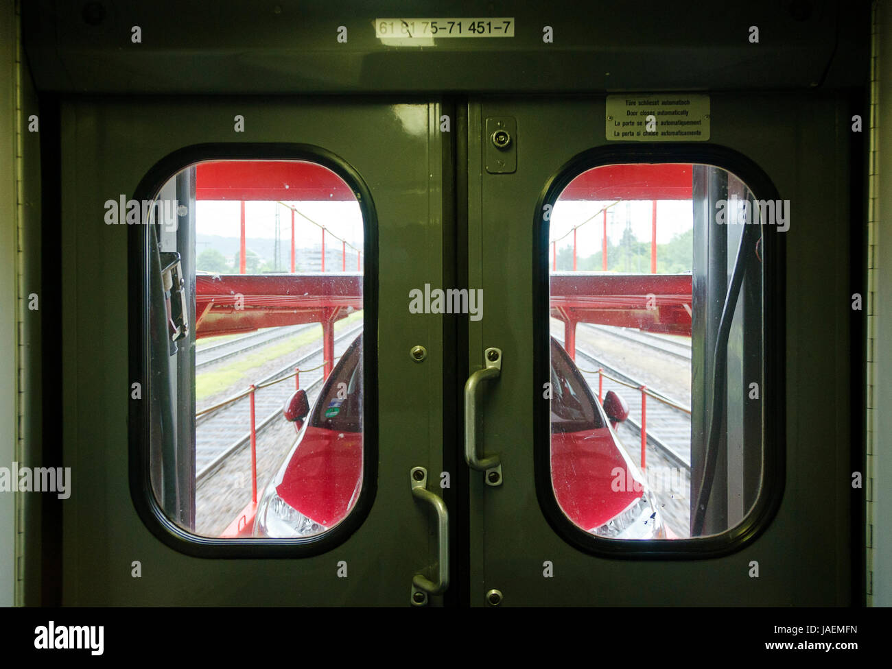 Blick durch Waggonfenster auf Autoreisezuganhänger mit rotem Pkw; View through window of a coach at car train wagon with red motor car Stock Photo