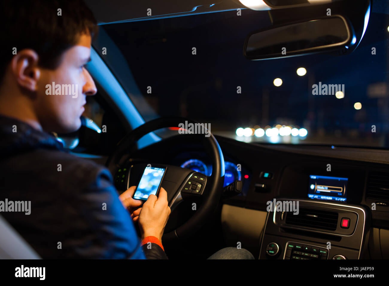 Driving a car at night -man driving his modern car at night in a city ...