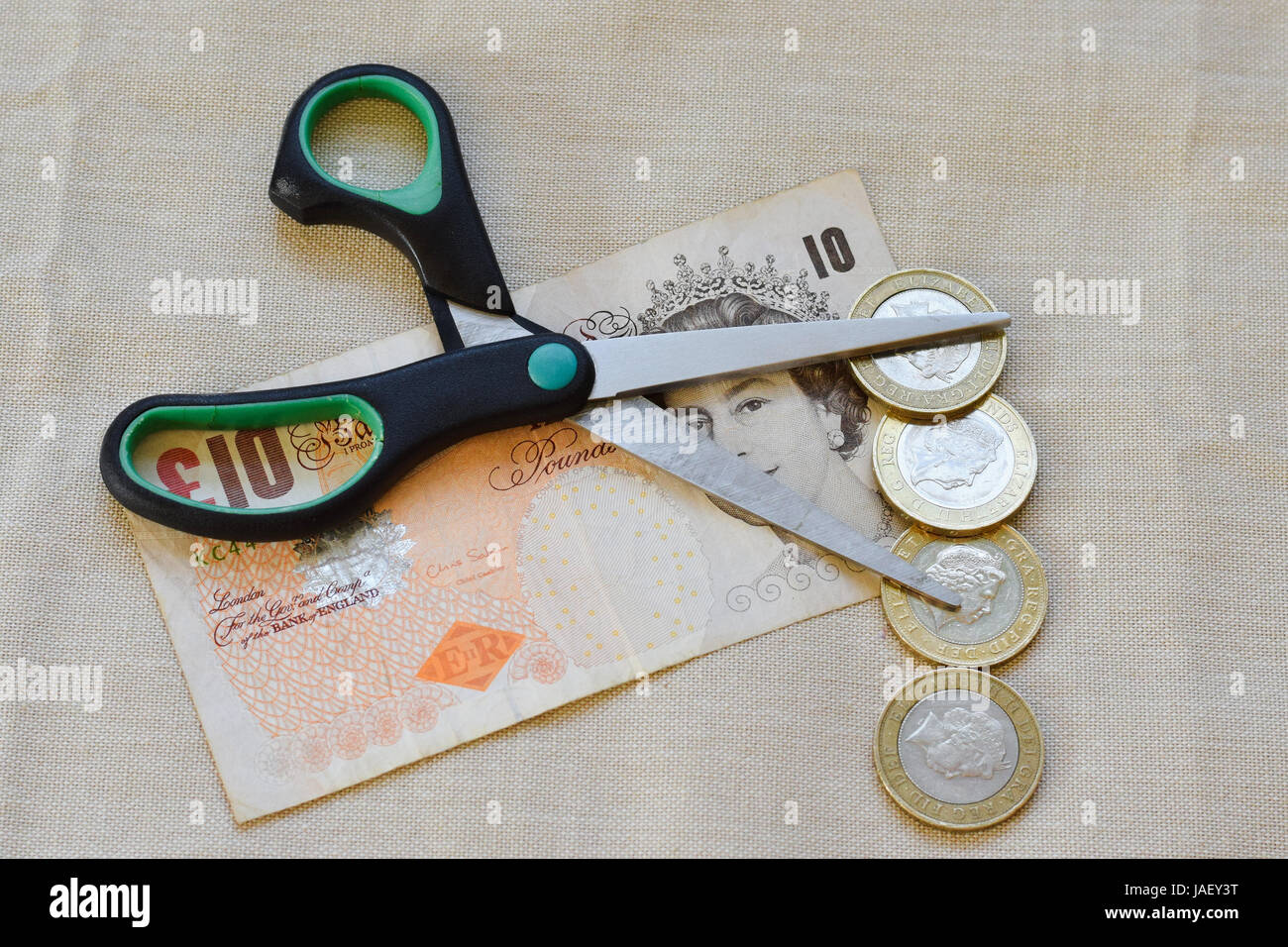sterling note with open scissors and pound coins on top Stock Photo