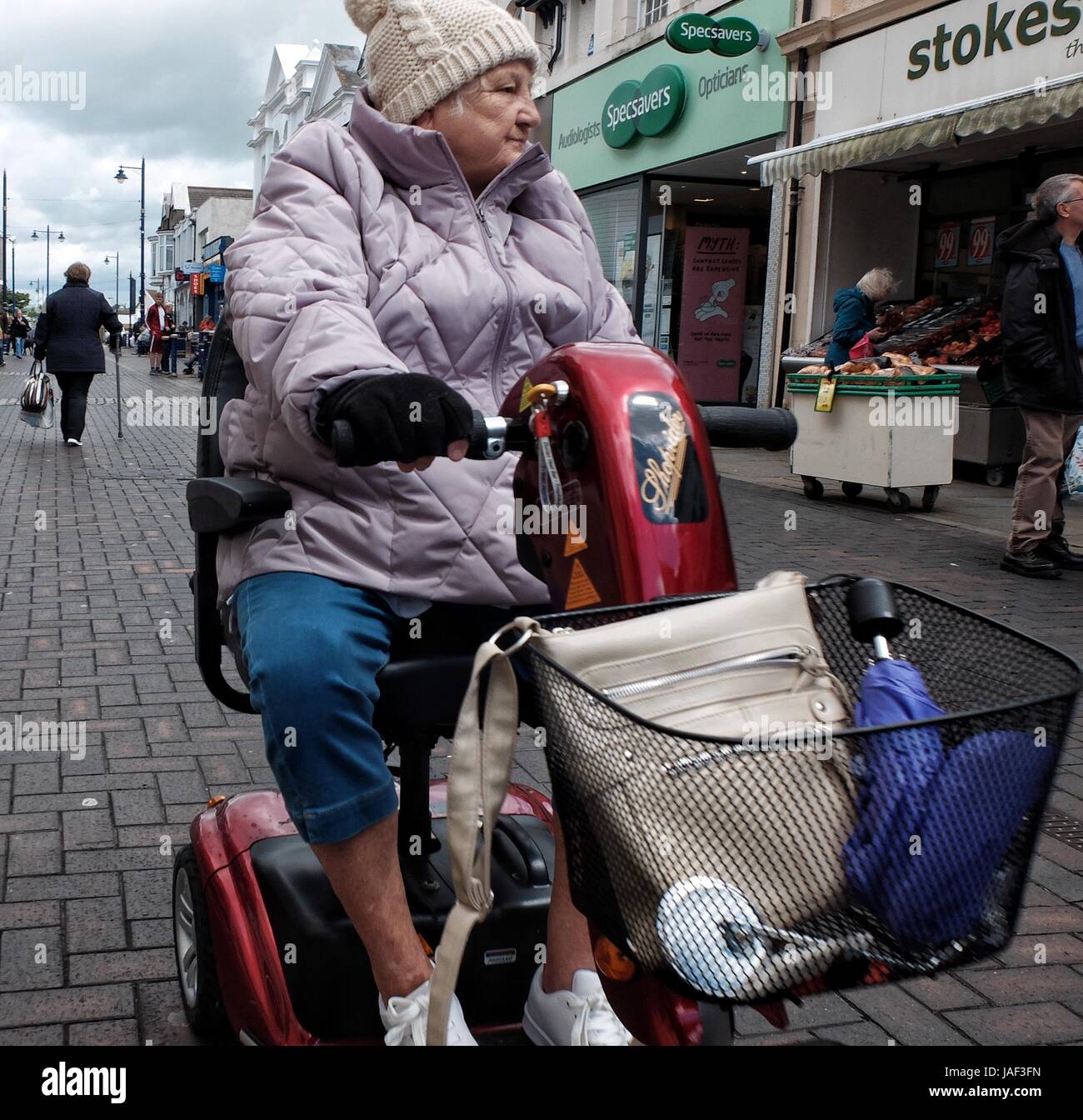 An elderly lady uses a mobility scooter in Porthcawl, South Wales Stock