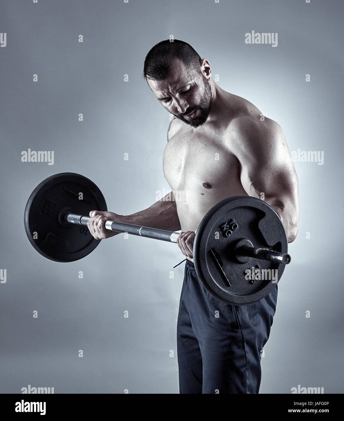 Man doing biceps curl with barbell in studio Stock Photo - Alamy