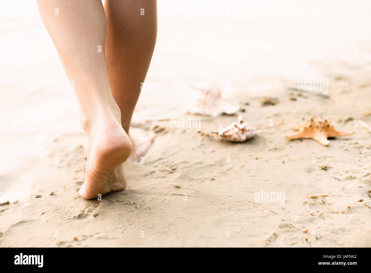 Woman walking on sand beach leaving footprints in the sand Stock Photo ...