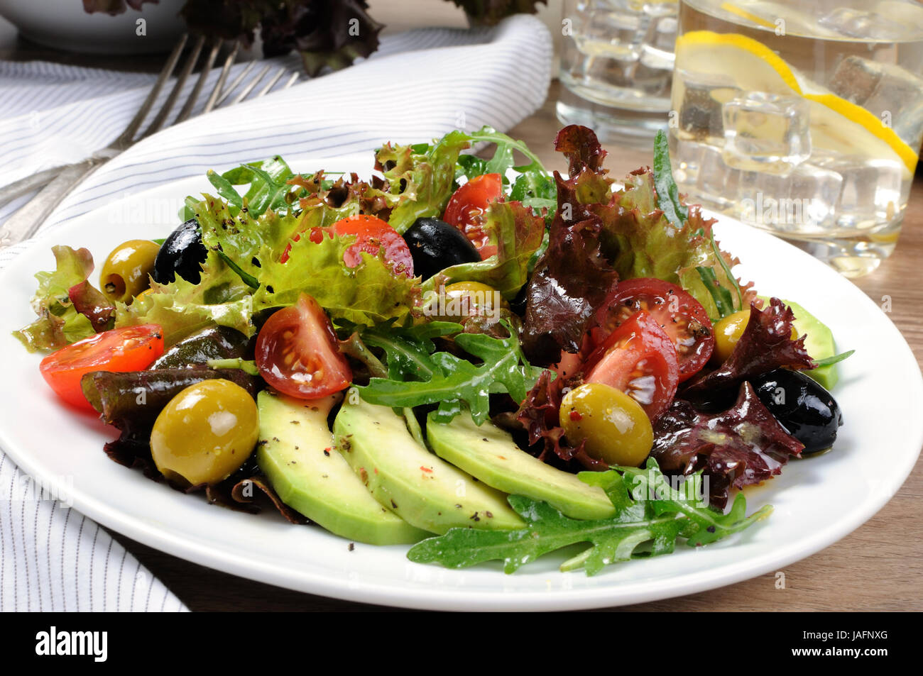 Summer salad - with avocado, olives, tomatoes in lettuce dressed, mustard-garlic sauce Stock Photo