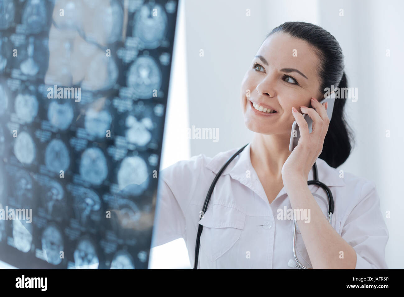 Lets face the result of brain checkup. Delightful cheerful professional neurologist working at the clinic while looking at ct scan result and having c Stock Photo