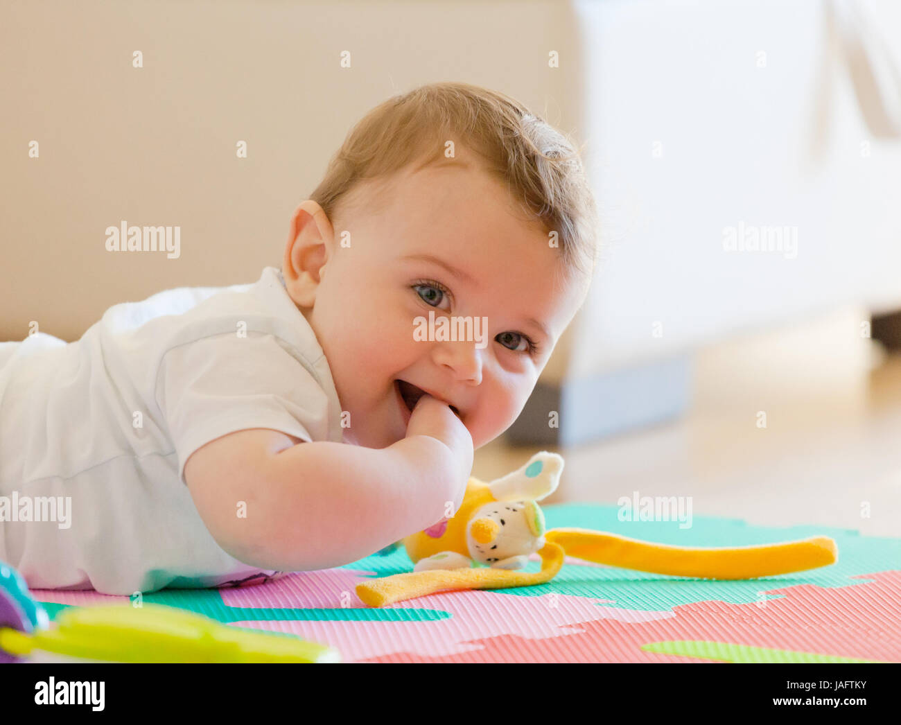 Toddler plays on the colored rubber mat. Stock Photo