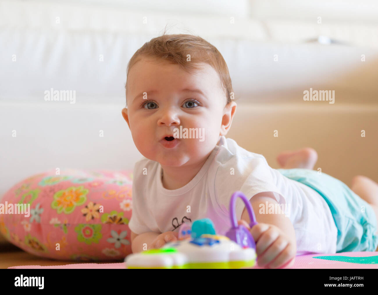 Toddler plays on the colored rubber mat. Stock Photo