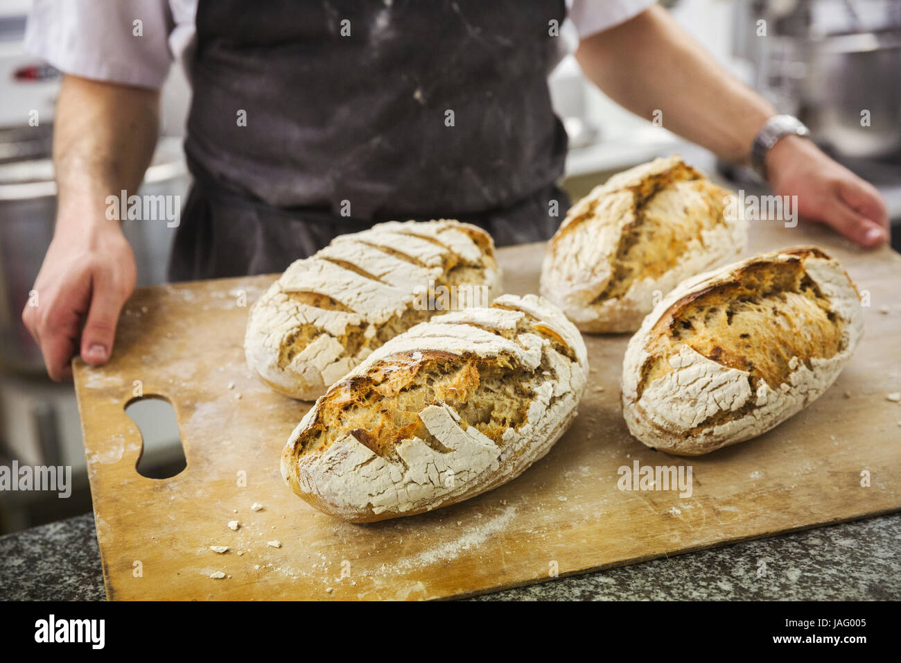 Baker holding tray with freshly baked loaves of bread. Stock Photo