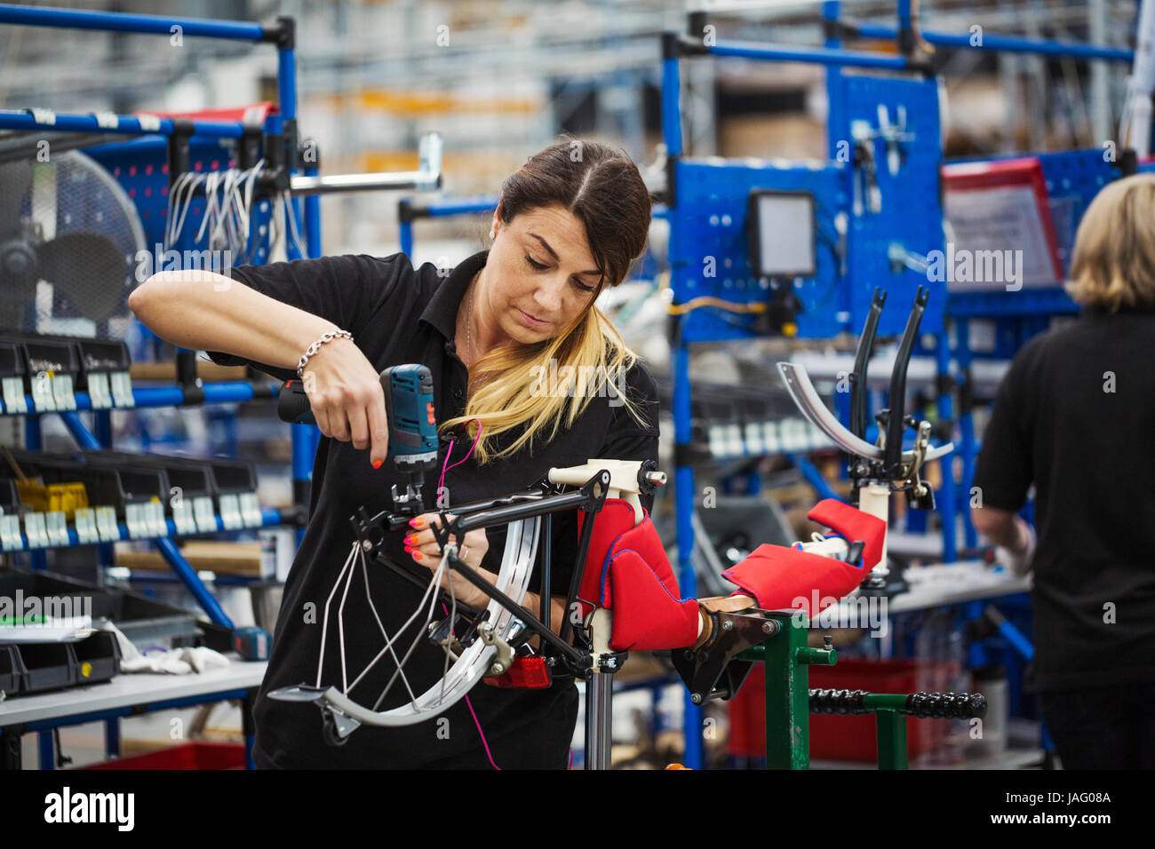 Female skilled factory worker assembling a bicycle in a factory working on the frame and wheels