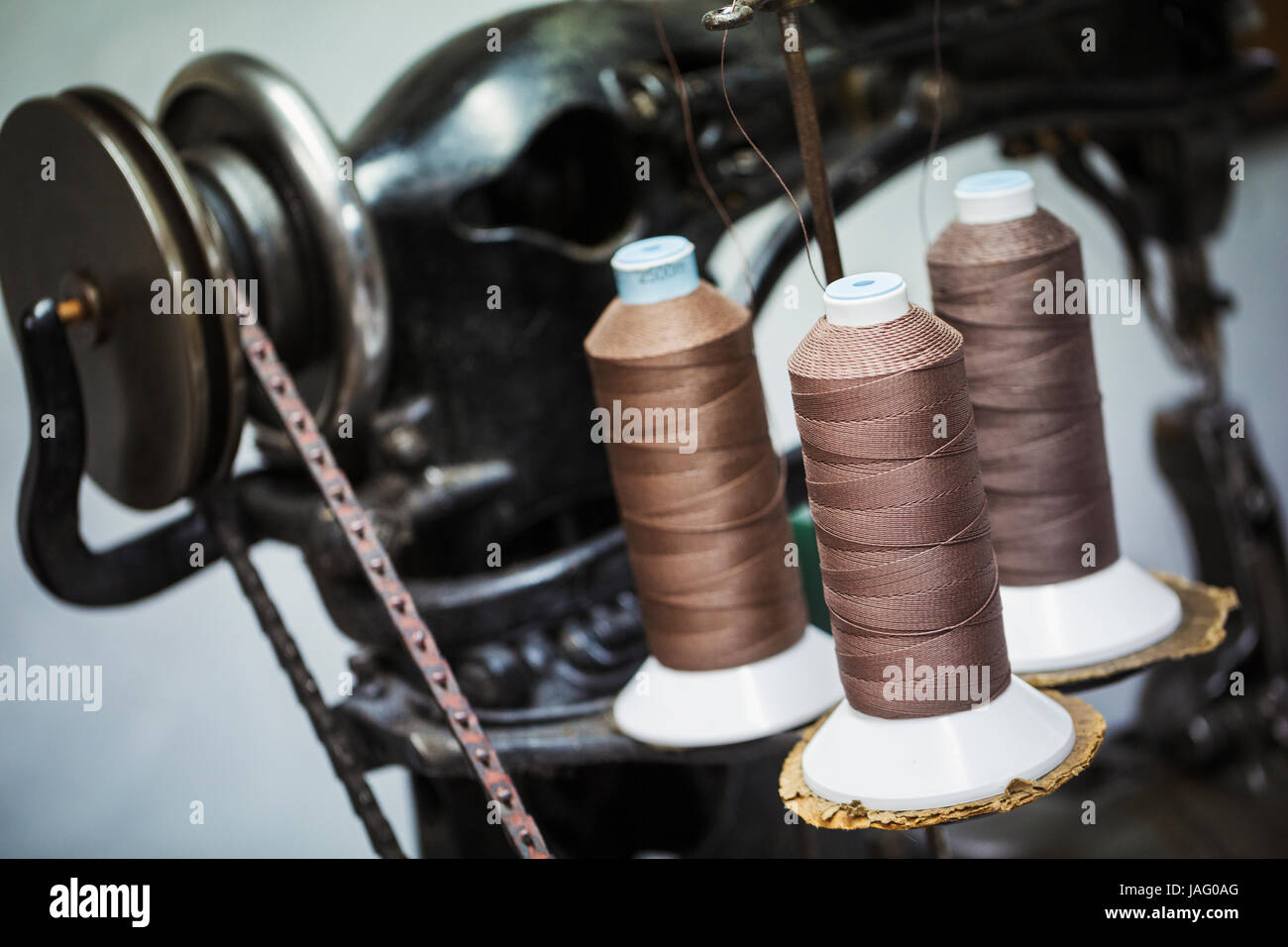 Close up of an indistrual leather sewing machine with spools of strong twine or thread in a