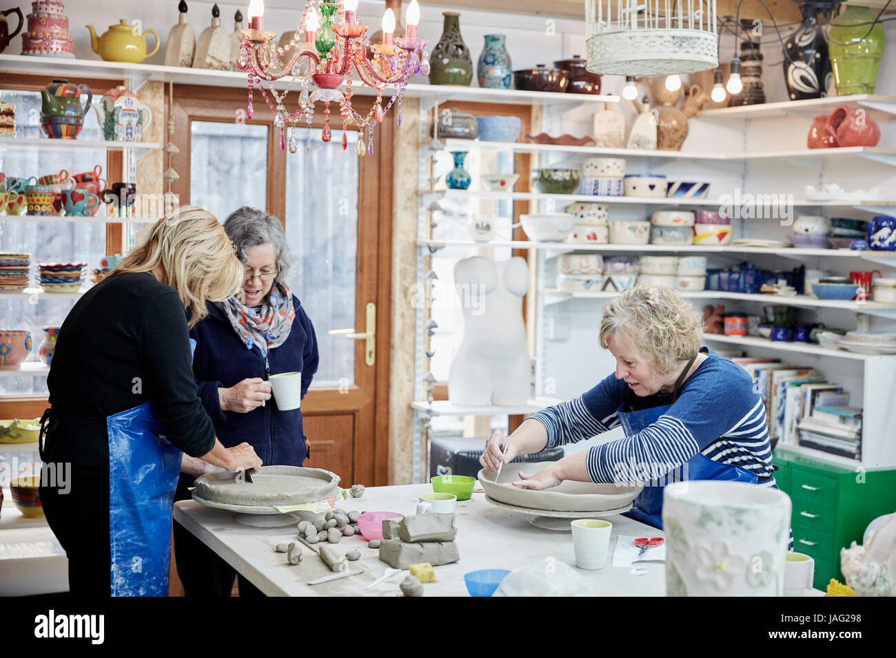 Three women in a pottery studio working with clay. Stock Photo