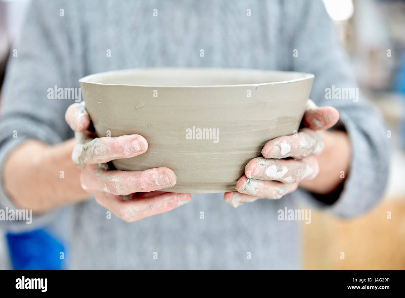 A person holding a freshly thrown clay pot with gently sloping sides. Stock Photo