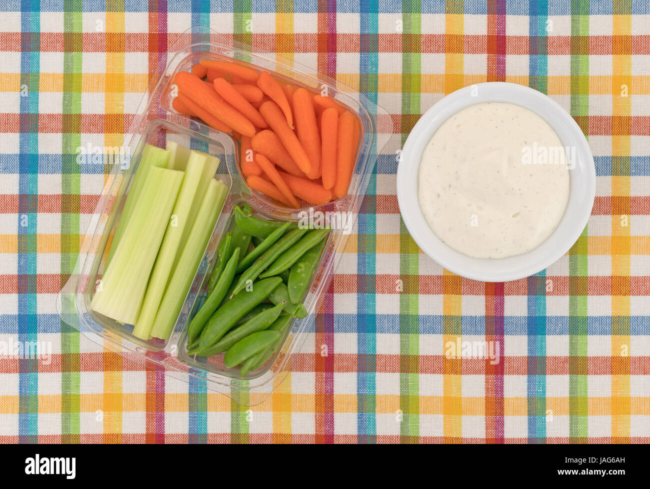 Top view of celery, carrots and sugar snap peas in a plastic container
