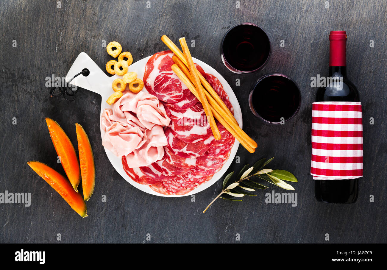 Cold meat cut from different varieties of salami on a dark background
