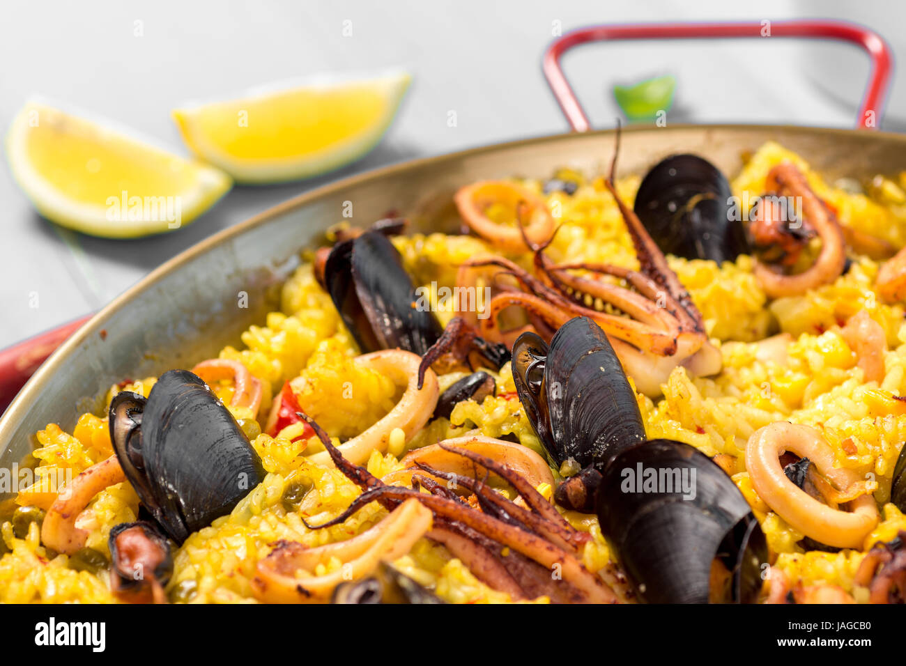 Seafood Paella in Traditional Pan on Rustic Wooden Table Stock Photo