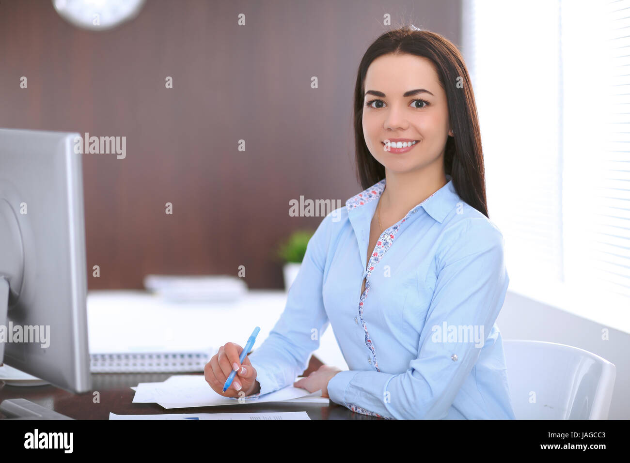 Young business woman sitting a at the table in office Stock Photo - Alamy