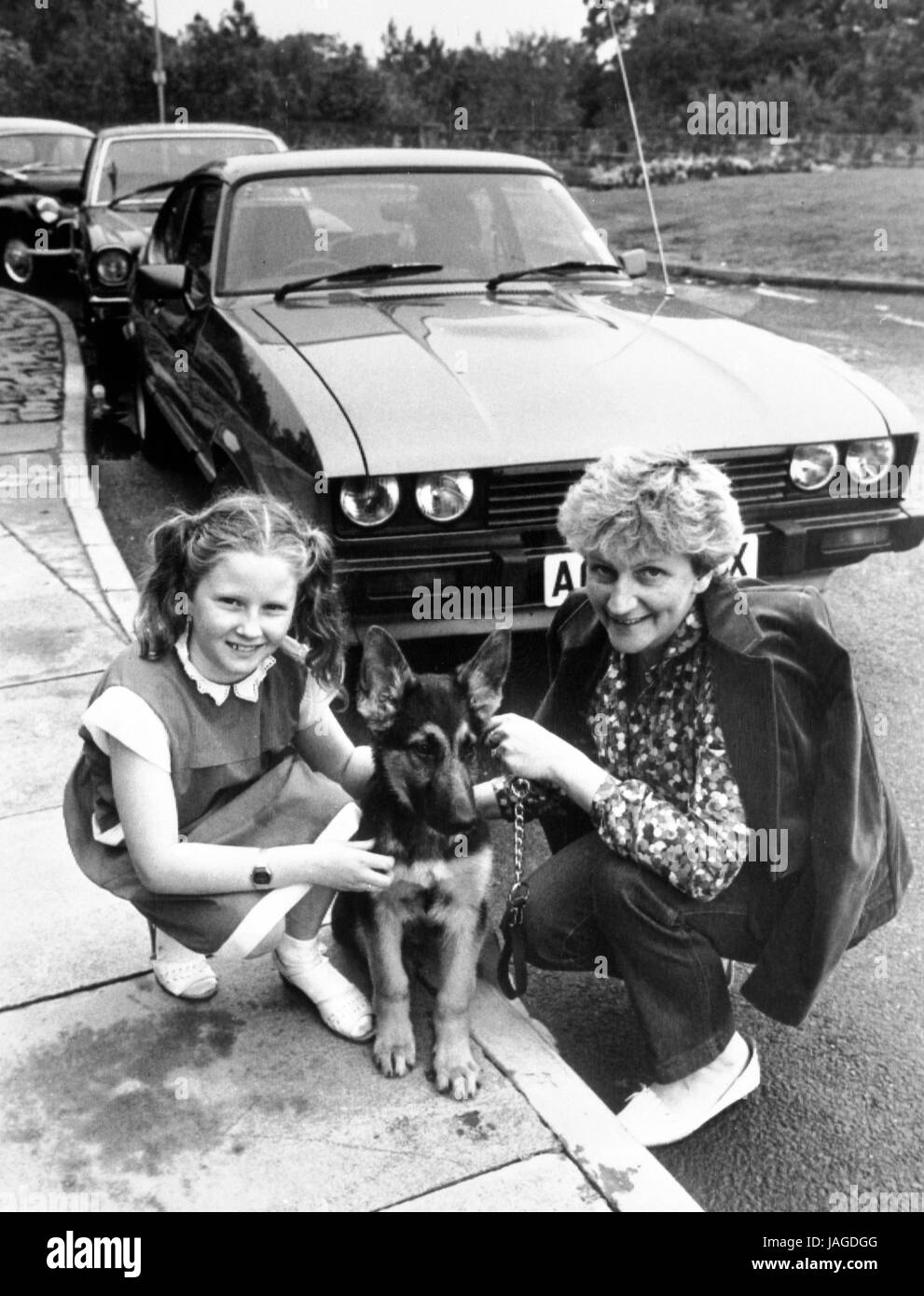 Elizabeth Parrie, 9, and her German Shepherd pup, Rocky, in Liverpool with Elizabeth's mother Rosemary. Earlier the girl and her pup were curled up on the back seat of a Ford Capri (in background) when car thieves drove off in the vehicle. When Rocky barked the startled thieves abandoned the car and fled. Stock Photo