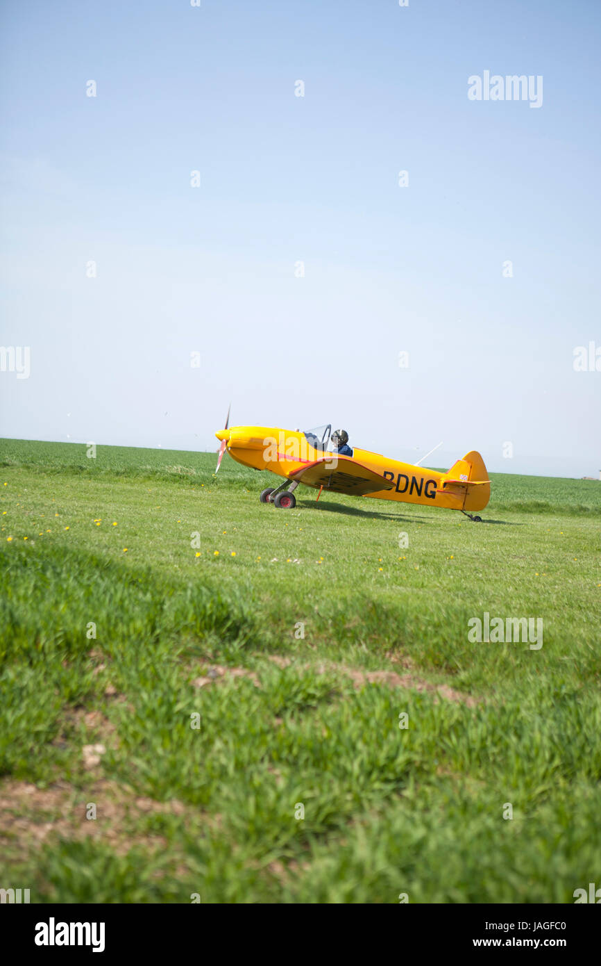 very small yellow aircraft taxiing along rural field ready to take off for flight Stock Photo