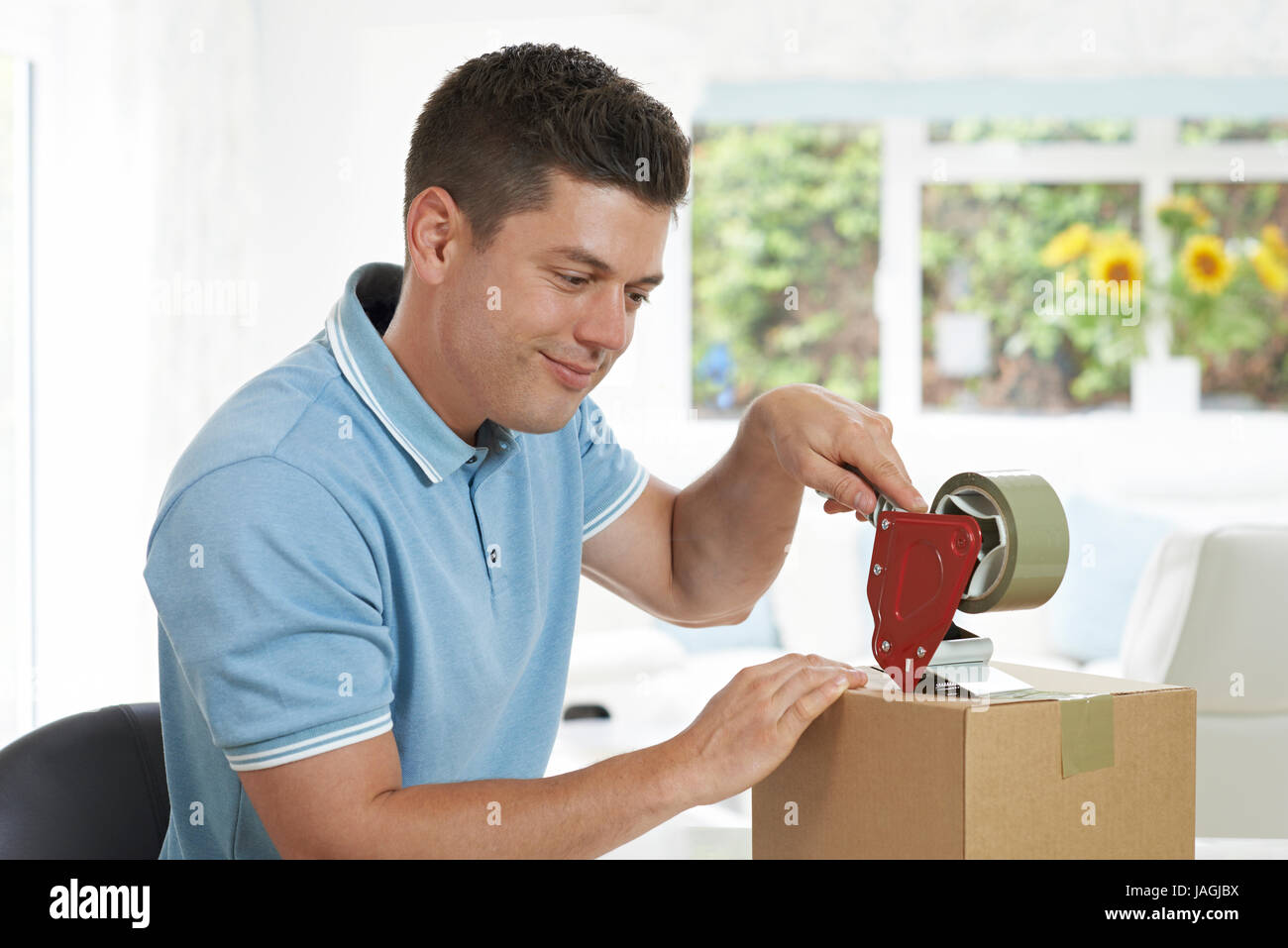 Man At Home Sealing Box For Dispatch Stock Photo