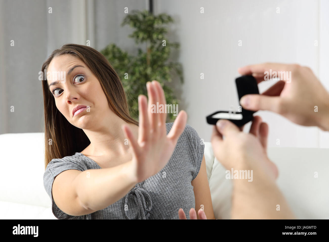 Scared girlfriend rejecting a marriage proposal at home. Humorous situation Stock Photo