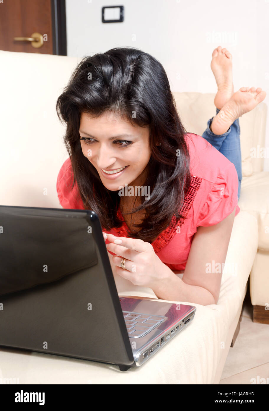 Smiling Young Woman Lying On The Couch Surfing The Internet With Her Laptop Computer Concept 