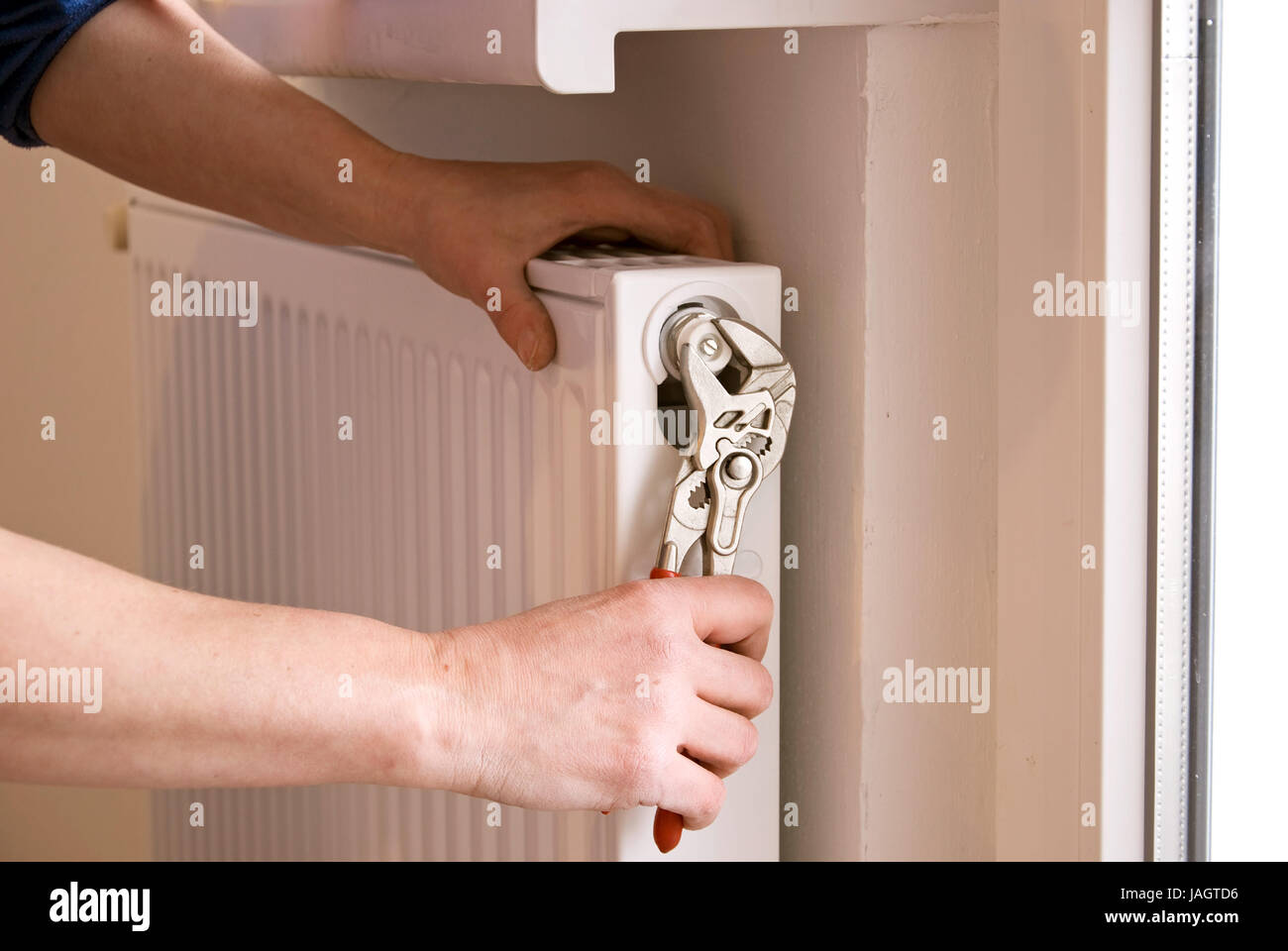 plumber fixing a radiator with pliers on a construction site Stock Photo
