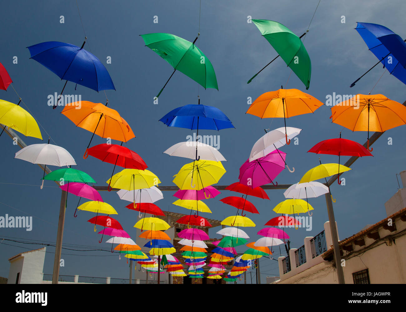 A display of brightly coloured umbrellas hanging above a street in