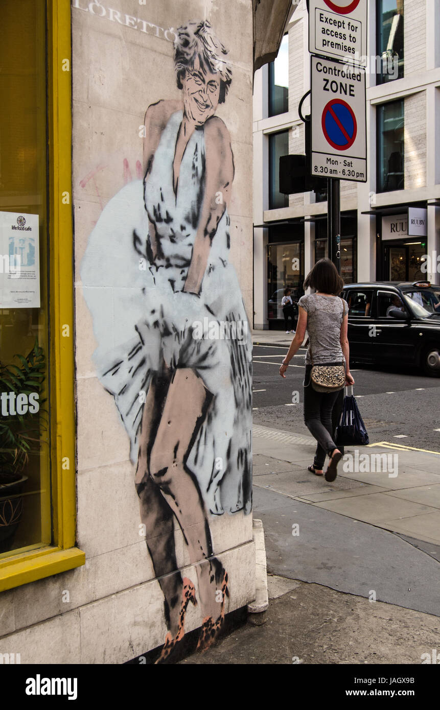 LONDON, UK - JUNE 1, 2017:  Pedestrians and drivers going past a piece of street art graffiti by Lorenzo showing Prime Minister Theresa May wearing he Stock Photo