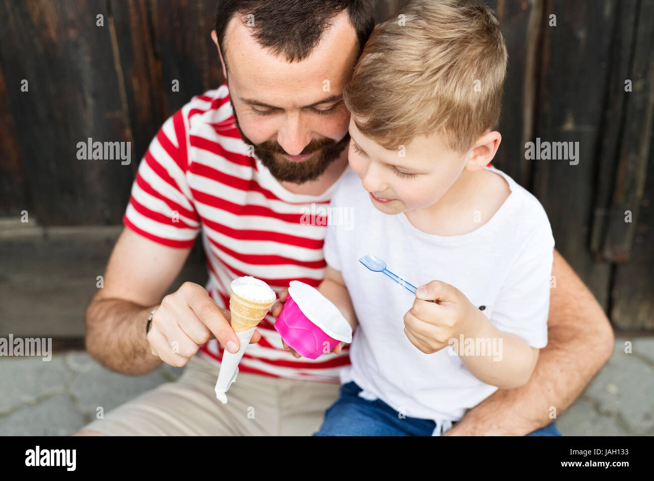 Young father and his little son eating ice cream. Sunny day. Stock Photo