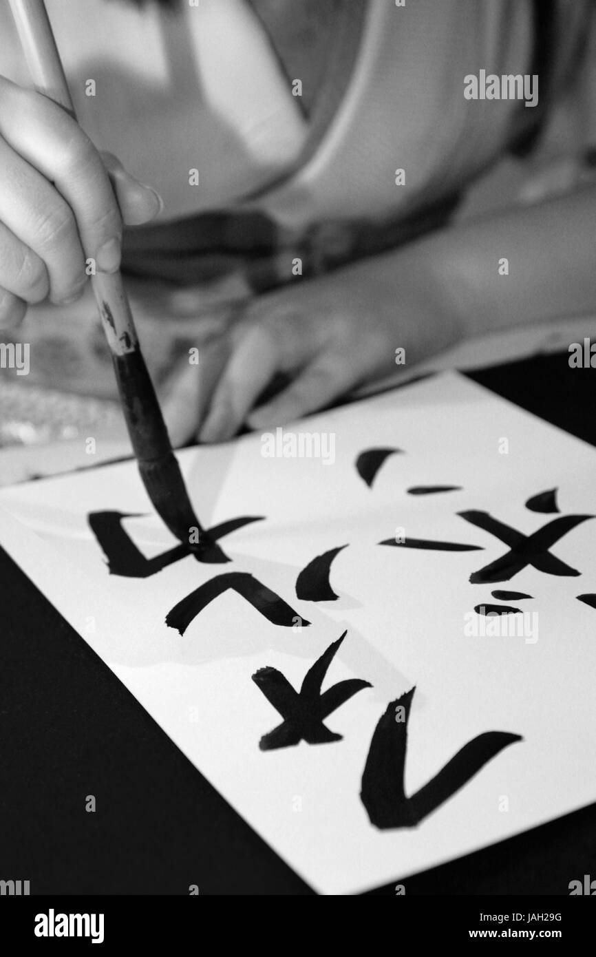 Asian woman paints Kanji characters on paper, Stock Photo