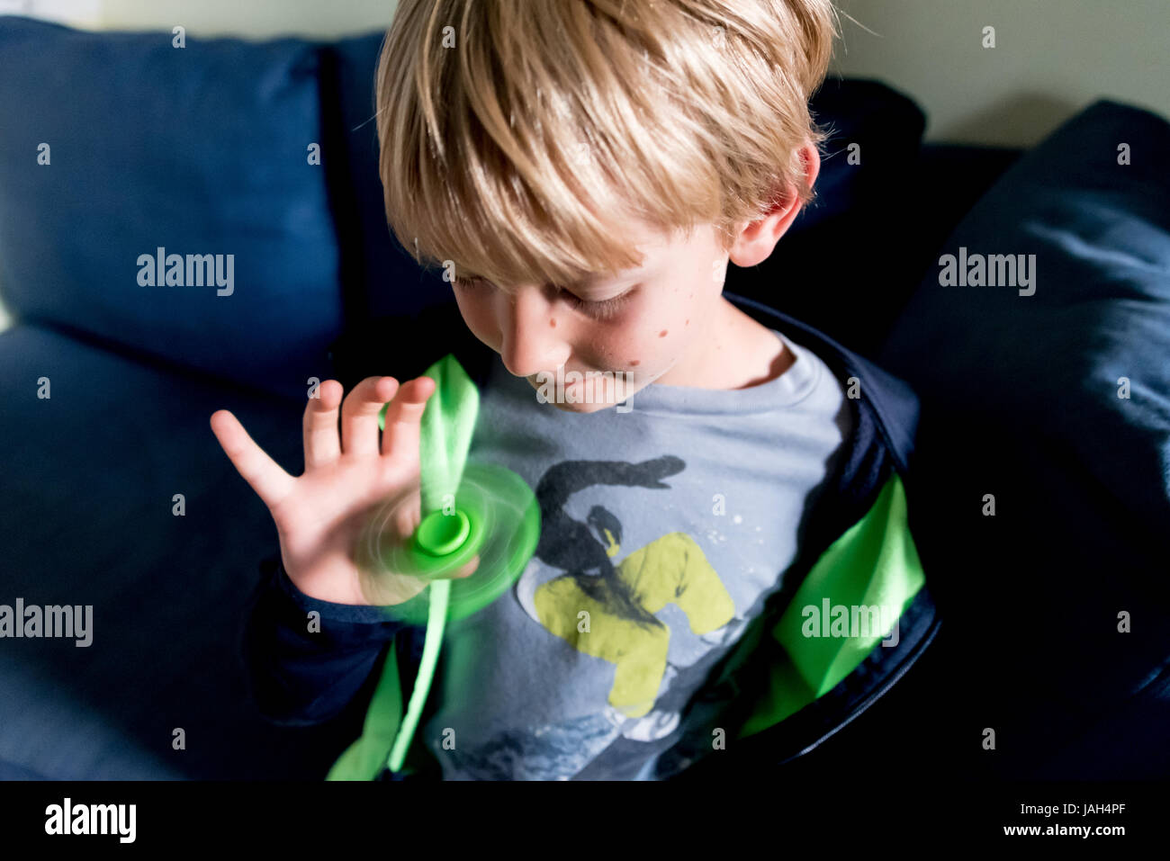 A boy plays with a fidget spinner at home, the controversial stress relief toy found to help some antsy or autistic children concentrate in school Stock Photo