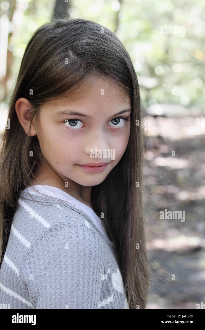 Young pre-teen kid with long hair looking directly into the camera. Stock Photo