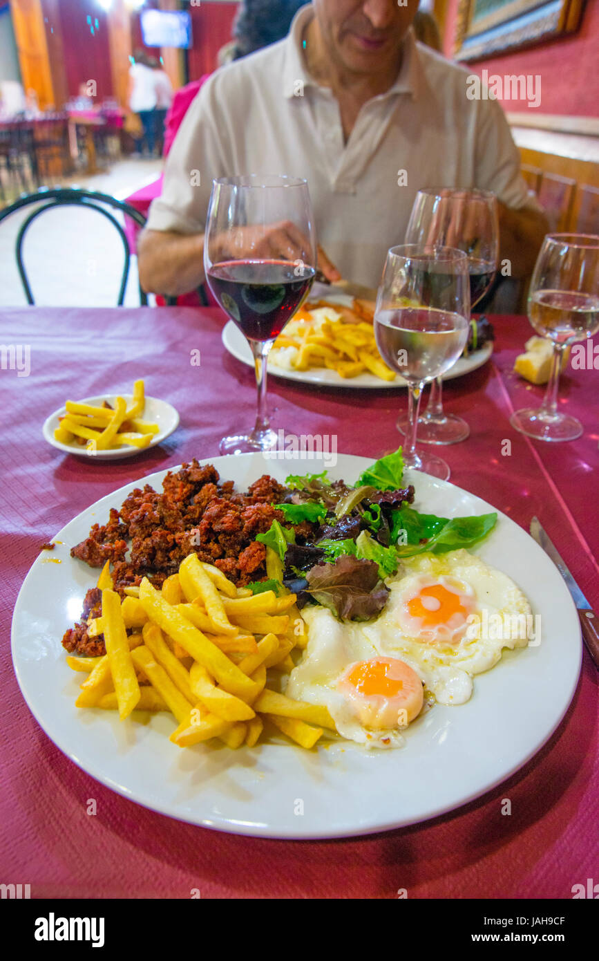 Fried eggs with chips, picadillo and salad in a restaurant. Spain. Stock Photo