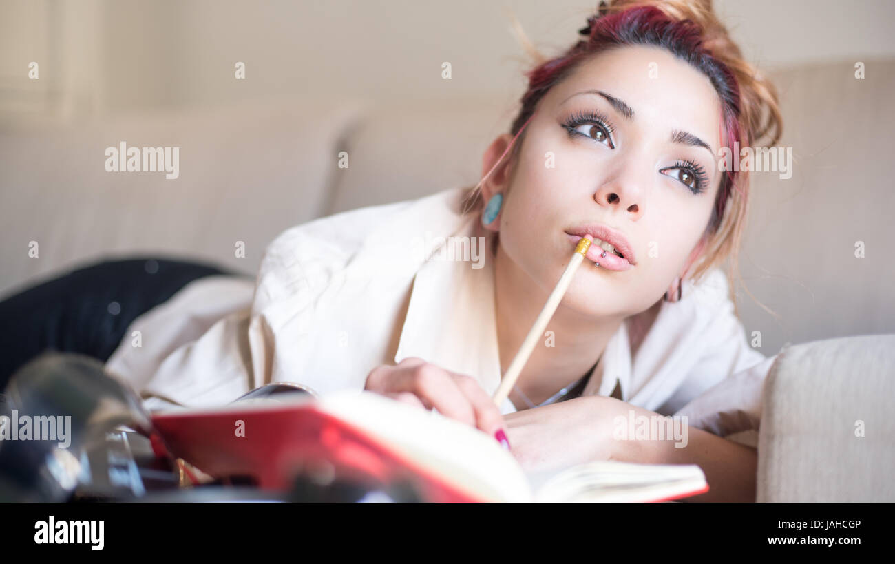 Young creative woman at home writing movie script and looking up for enlightenment Stock Photo