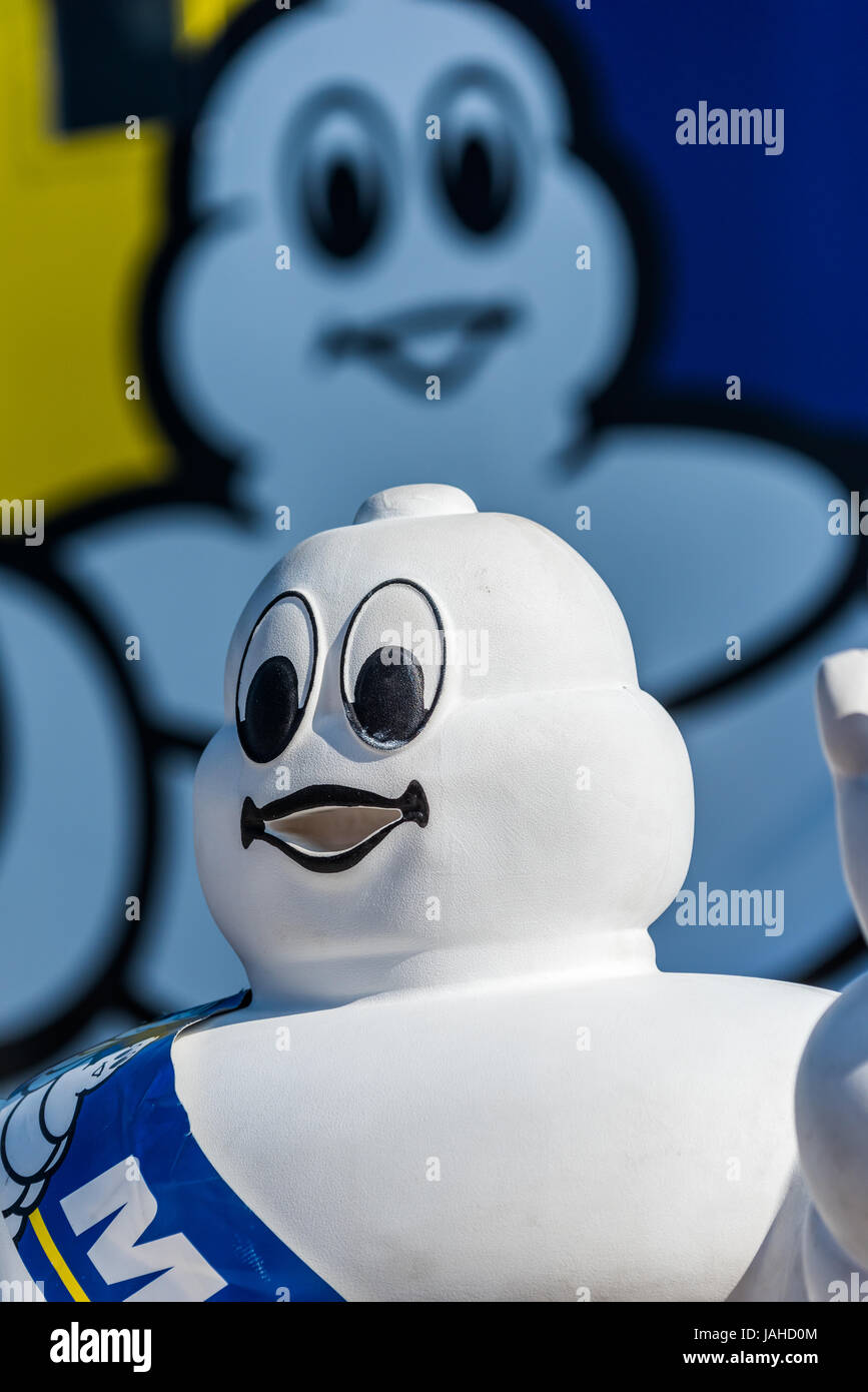 A promotional three dimensional 'Michelin Man' stands against the two dimensional graphics on the Michelin tyre truck. Stock Photo