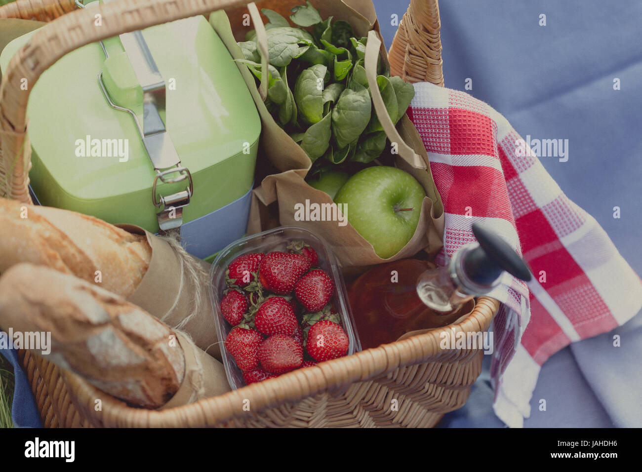 Summer basket for picnic with wine, bread, fruits and snacks in park ...