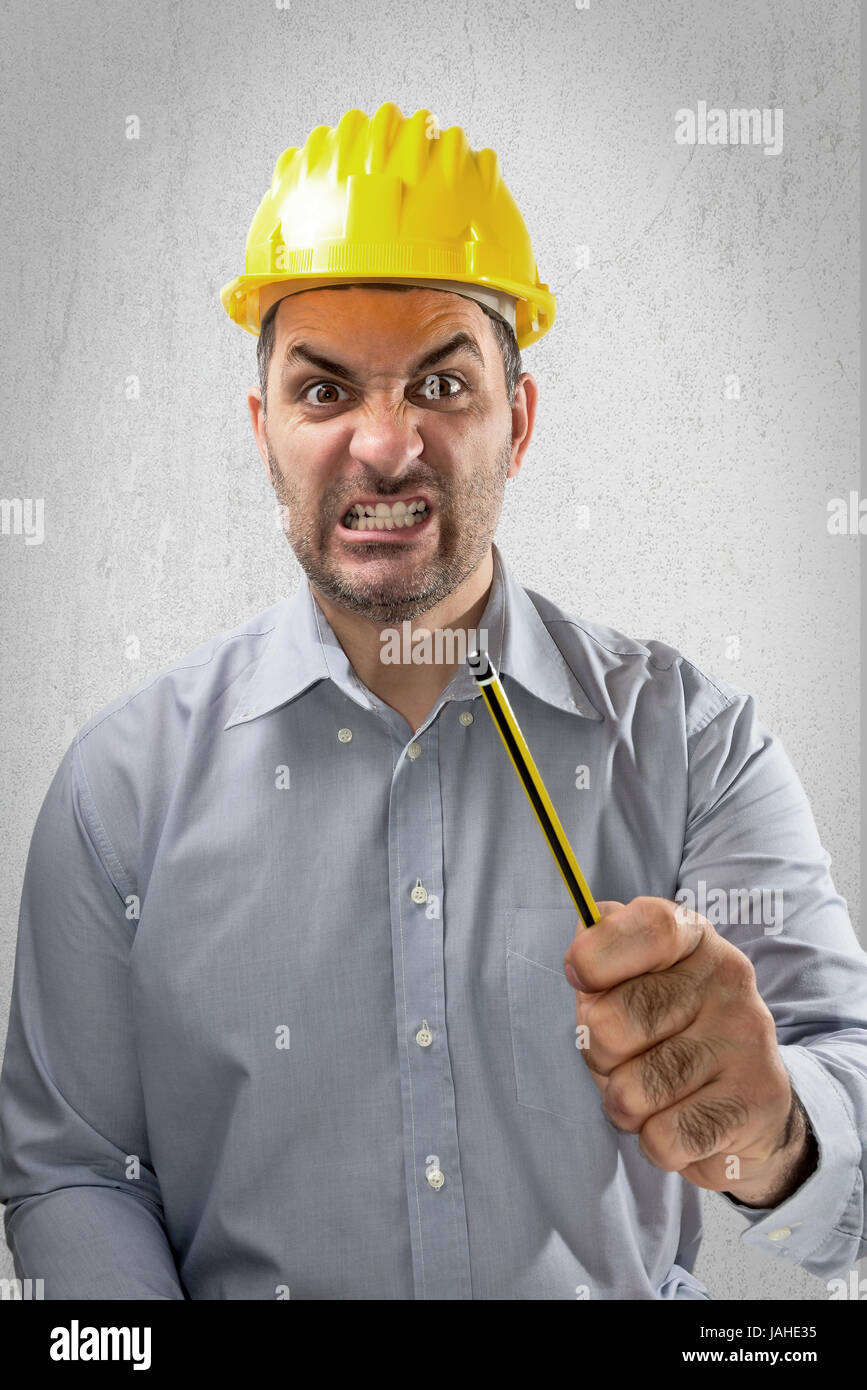Angry Engineer with a helmet on his head, shakes the hand with a pencil Stock Photo