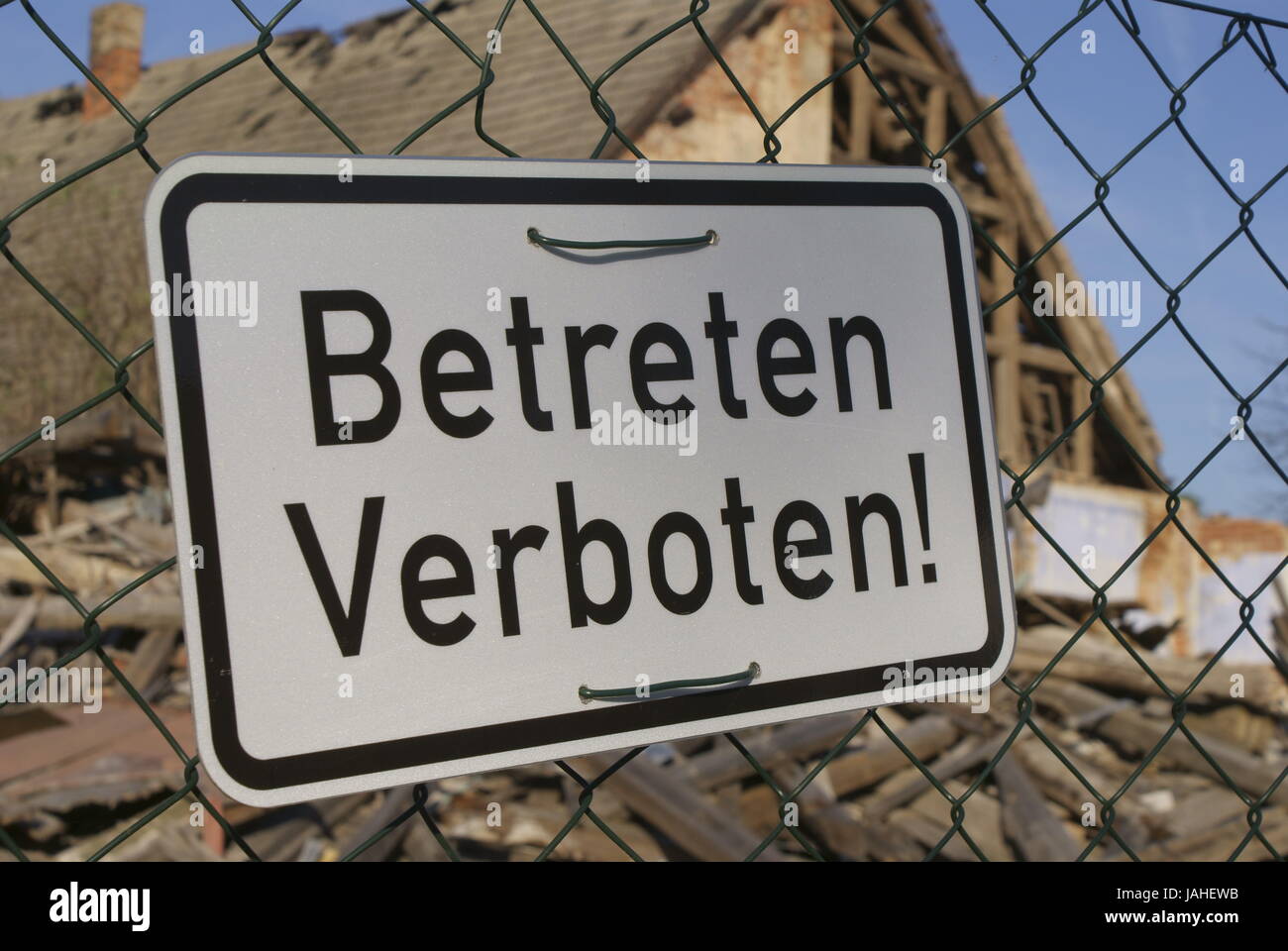 silbernes Schild mit schwarzer Schrift ' Betreten Verbote' vor einer Ruine hängend Stock Photo