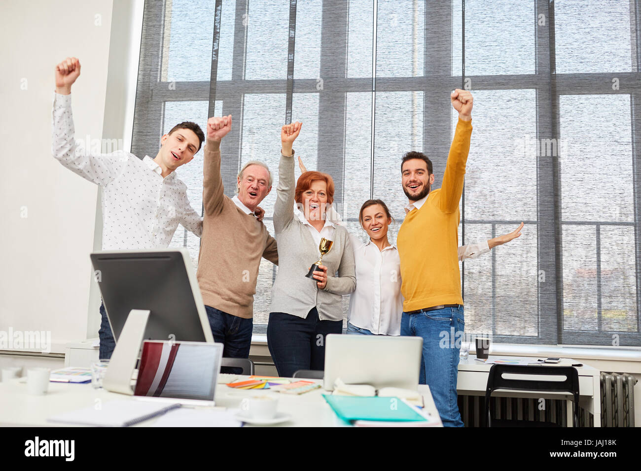Start-up team cheering about their success with winner trophy Stock ...